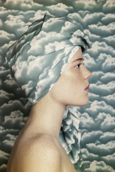 a woman with a turban on her head standing in front of a cloudy sky