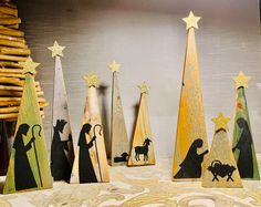 wooden christmas trees with nativity scene painted on them and gold stars in the top