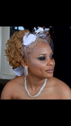 a woman wearing a veil with flowers on her head and pearls in her hair is looking at the camera