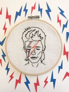 an embroidered portrait of a man with red, white and blue arrows in the background