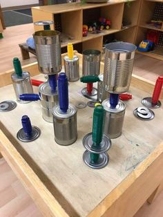 an assortment of tin cans sitting on top of a wooden table in a playroom