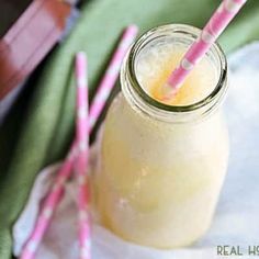 two pink and white striped straws in a mason jar next to some bananas on a green cloth