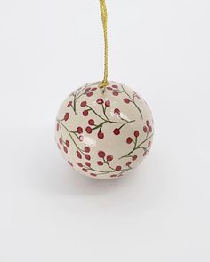 a white ornament with red berries hanging from it's side on a yellow cord