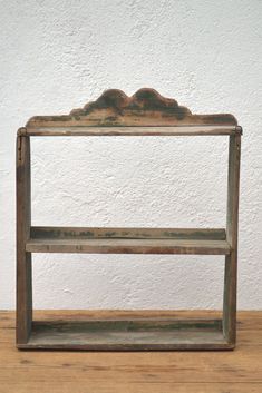 an old wooden shelf sitting on top of a wooden floor next to a white wall