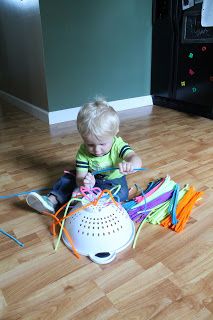 a toddler sitting on the floor playing with some colorful items in front of him