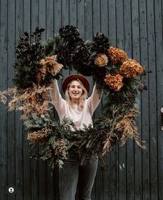 a woman standing in front of a green wall holding a wreath