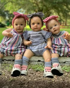 three dolls are sitting on a bench in the park