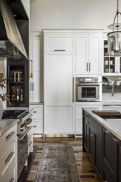 a large kitchen with white cabinets and black counter tops, an area rug on the floor