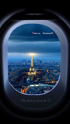 an airplane window with the eiffel tower at night