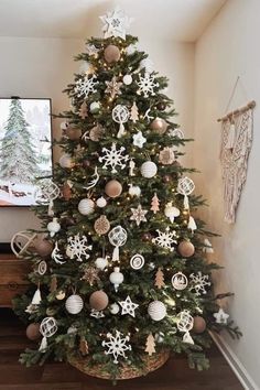 a decorated christmas tree in the corner of a room with a flat screen tv on