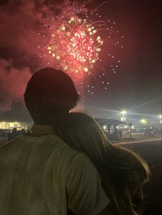 a man and woman looking at fireworks in the sky