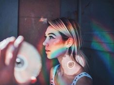 a woman holding a disc in front of her face with the light coming through it