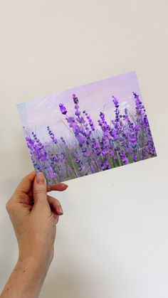 a hand holding up a card with purple flowers