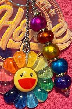 a multicolored sunflower keychain hanging from a metal chain on a pink towel