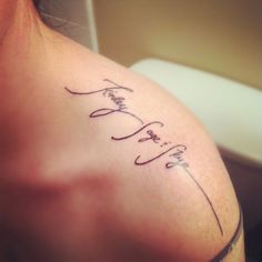 a woman with a tattoo on her shoulder that says faith and two swords in cursive writing