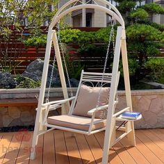 a white swing chair sitting on top of a wooden deck