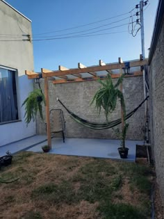 a hammock is in the middle of a yard with two potted plants