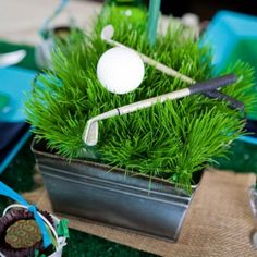 a golf themed centerpiece is displayed in a potted planter on the table