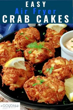 crab cakes on a black plate with lemon wedges