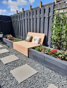 a wooden couch sitting in the middle of a graveled area next to a fence