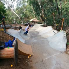 two skateboarders riding on ramps in the woods