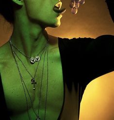 a woman with green paint on her face and necklaces in front of her face