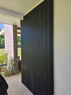 an open door leading to a patio with black slatted walls and white tile flooring