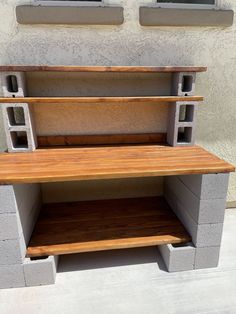 a bench made out of cinder blocks and wooden shelves on the side of a building