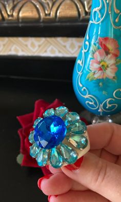 MARION GODART Paris Bague Fleur Bleu Strass taille 59 eu Spectacular statement rhinestone flower ring handmade by Marion Godart. It features a large blue faceted prong set rhinestone surrounded by 10 drop-shaped light blue rhinestones creating a mid-century style flower ring. The whole sits on a hard as glass white resin base-ring. This impressive ring measures a little over 1 3/4 inch diameter and 5/8 inch high, US ring size 9. This ring is unique, completely designed and handmade by Marion Godart in her Paris studio.  Marion Godart is a well known French jewelry designer from Paris working with Resin, Lucite and Bakelite since the 1960's. She is known for her brightly colored quirky, yet chic costume jewelry. Inspired by artistic trends of the beginning of twentieth century, her creativi Sharon Miller, Paris Bracelet, French Jewelry, Bold Rings, French Designer, Rhinestone Flower, Rhinestone Ring, Cat Brooch, Blue Rhinestones