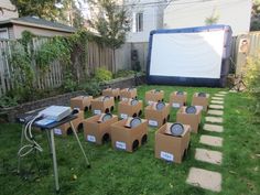 an outdoor movie is set up in the yard with cardboard boxes around it and a projector screen