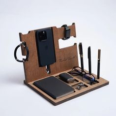 a cell phone, pen and glasses in a wooden holder