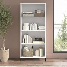 a white book shelf with books and plants