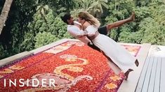 a man and woman dancing on top of a rug with trees in the back ground