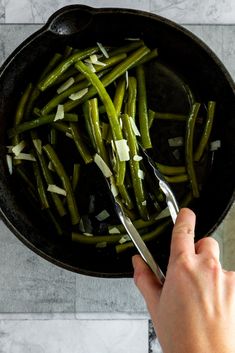 someone is cutting green beans into small pieces in a skillet on the counter top