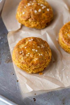 three carrot muffins sitting on top of a pan covered in wax paper and sprinkled with sea salt