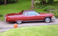 an old red car is parked on the side of the road