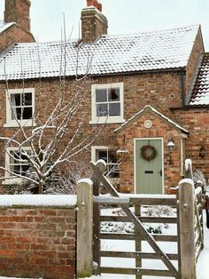 a brick house with a green door and snow on the ground in front of it