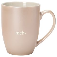 a pink coffee cup with the word meh on it's side and white lettering