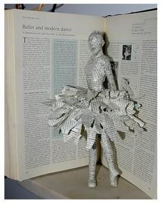 an open book with a paper cut out of the shape of a woman in a dress