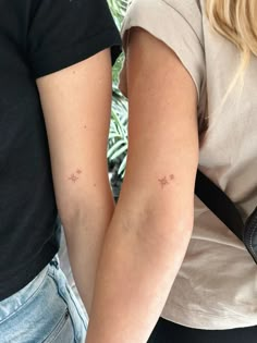 two people with small tattoos on their arms and armbands, both holding onto one another