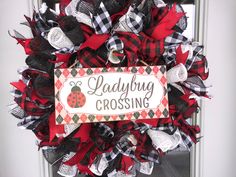 a ladybug wreath with the words ladybug crossing hanging on it's front door