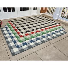 a black and white checkered area rug on the ground next to a porch with potted plants