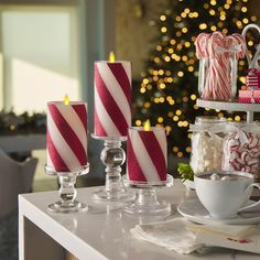 candy cane candles are sitting on a table next to other holiday decorations and candies