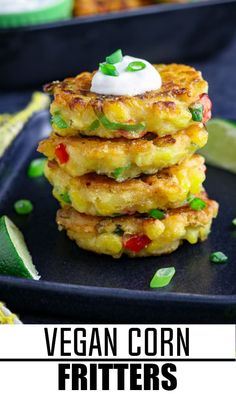 a stack of veggie fritters on a black plate with lime wedges