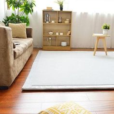 a living room filled with furniture and a white rug on top of a hard wood floor