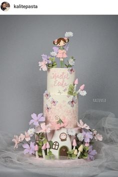 a three tiered cake with pink and white flowers on top is displayed in front of a gray background