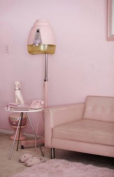 a living room with pink walls and a gold lamp on the floor next to a couch