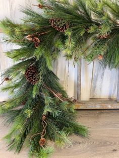 a pine branch with cones hanging from it's side on a wooden wall next to a window