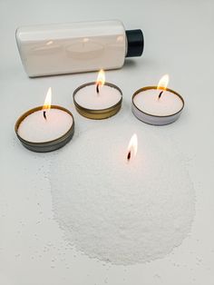 four candles are lit on a white surface