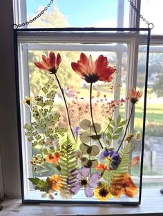 a window with some flowers in it on a chain hanging from the side of a building